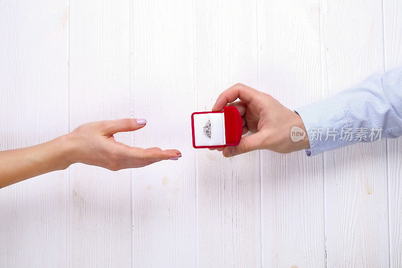 订婚/结婚/求婚场景。男子把昂贵的黄金白金钻石戒指给他的新娘的特写。